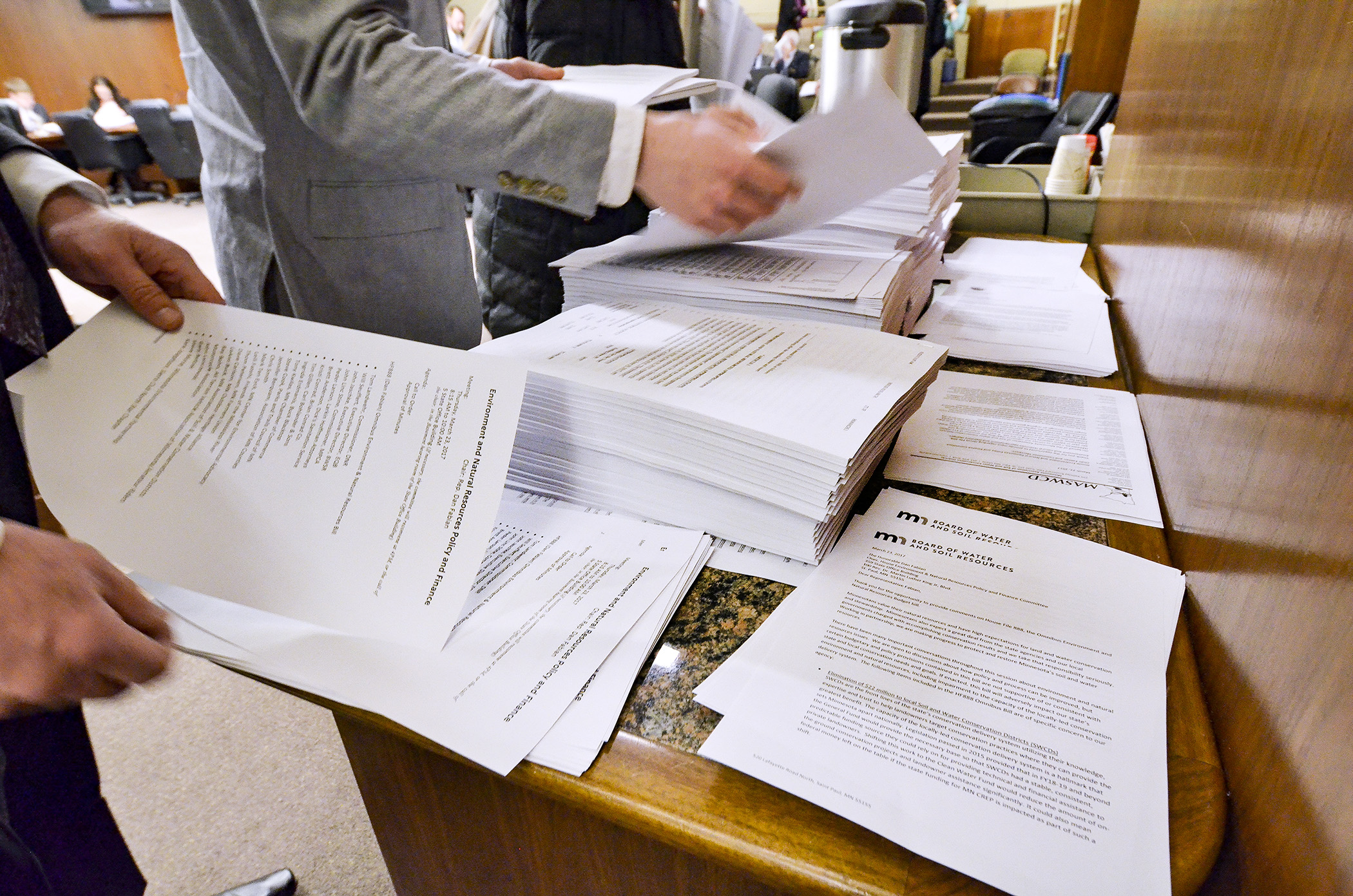 Interested parties pick up copies of the omnibus environment and natural resources bill during the March 23 meeting of the House Environment and Natural Resources Policy and Finance Committee. The committee did a walk-through of the bill Thursday. Photo by Andrew VonBank